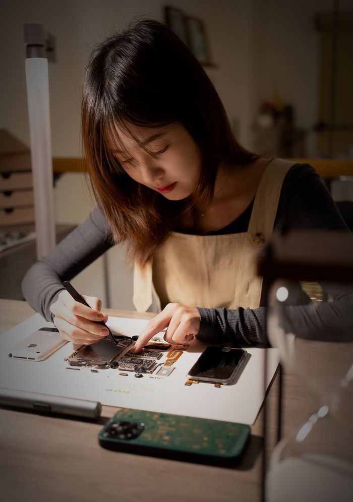 The Art of Drawing Readers In: Your attractive post title goes here Focused Asian woman repairing smartphone indoors in a workshop setting.