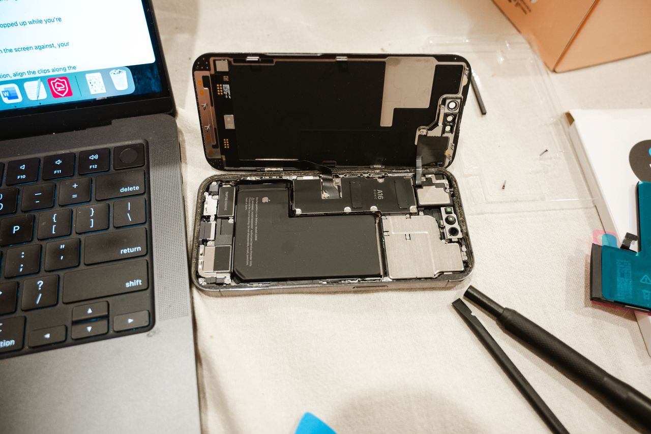 Mastering the First Impression: Your intriguing post title goes here Open iPhone with repair tools and laptop, showcasing DIY battery replacement process.